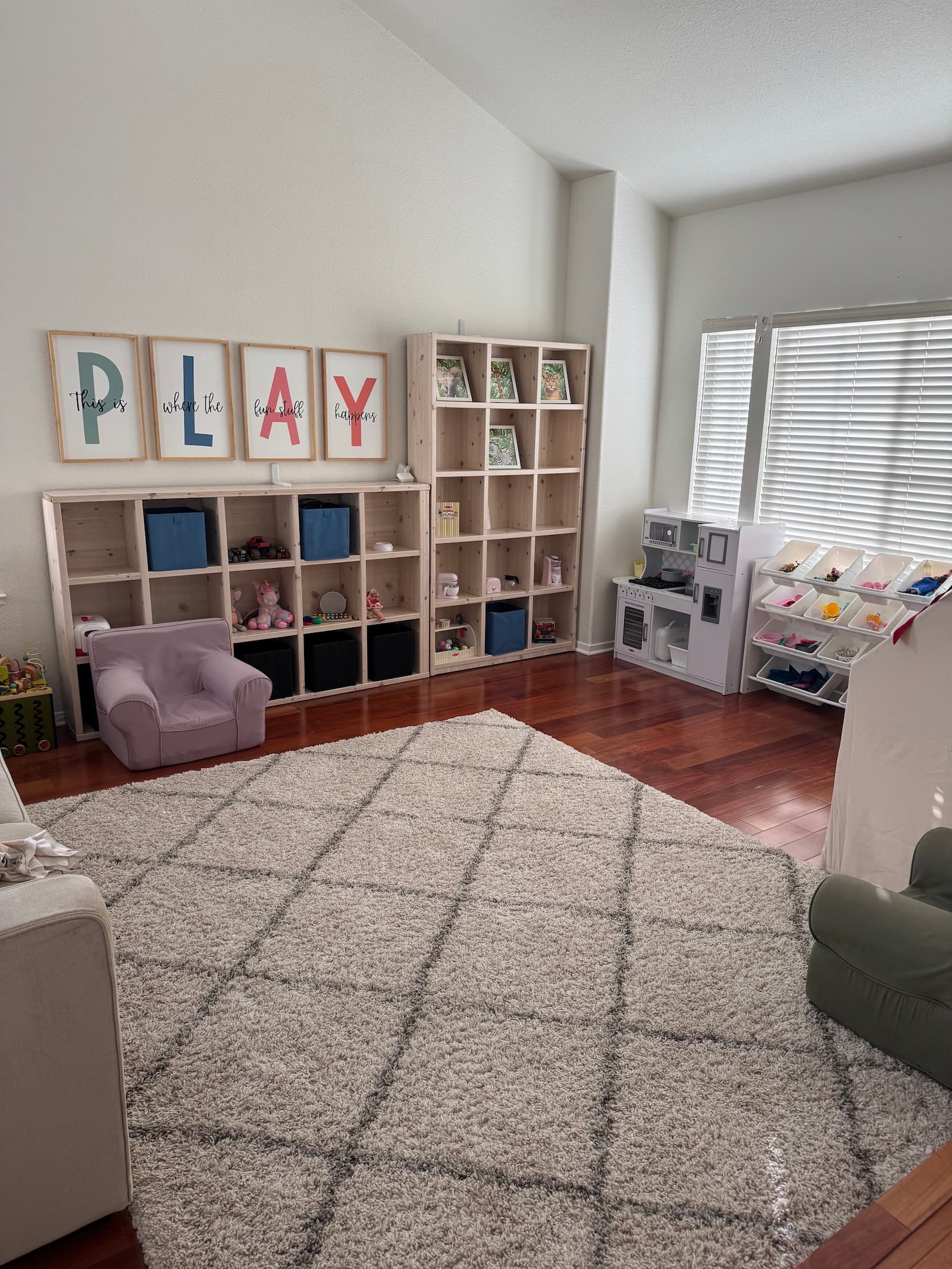 Our primary play area: reading nook, play kitchen, building blocks, and the PLAY wall art that anchors the room